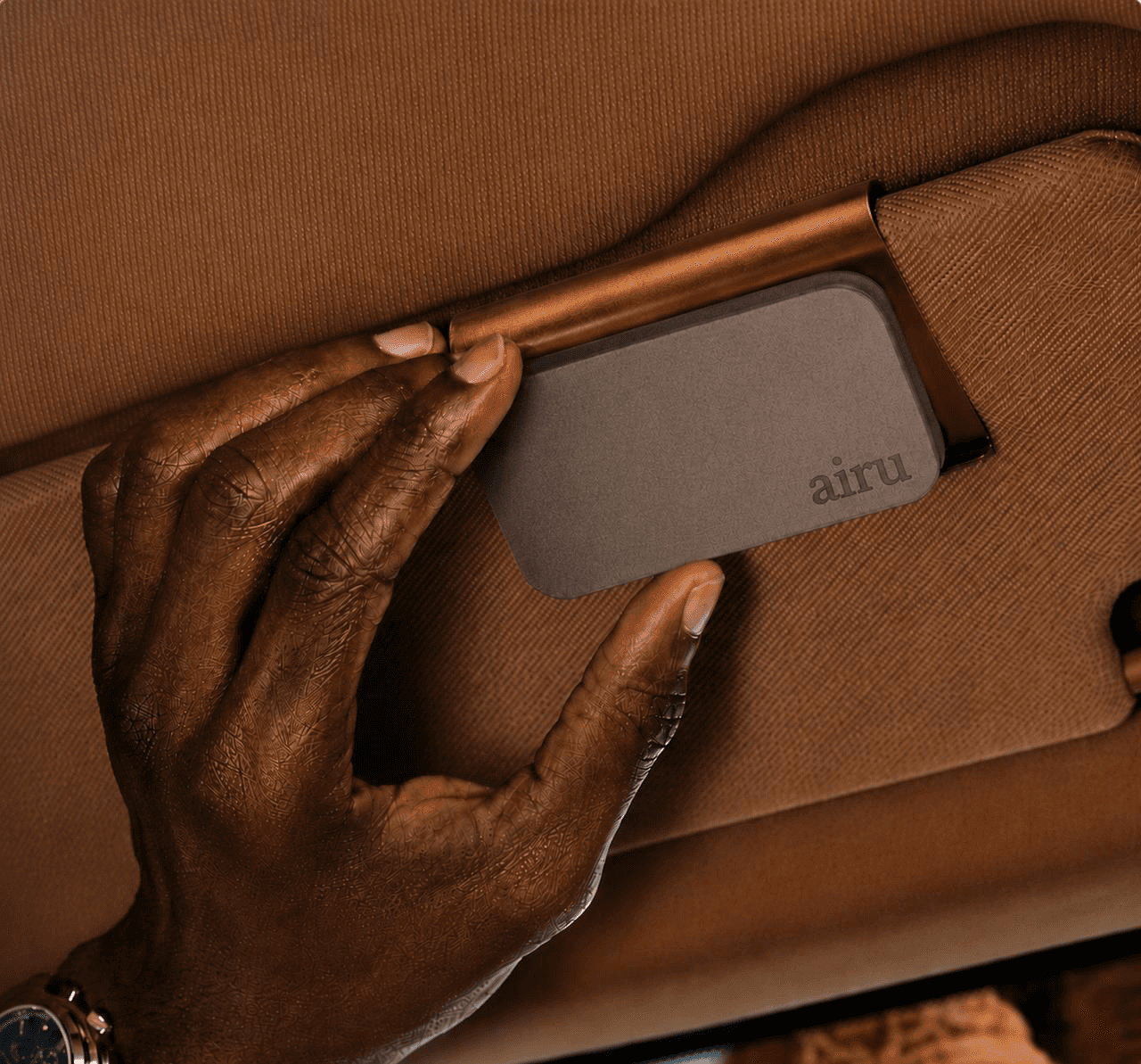 A hand clipping the airu tile to a car visor